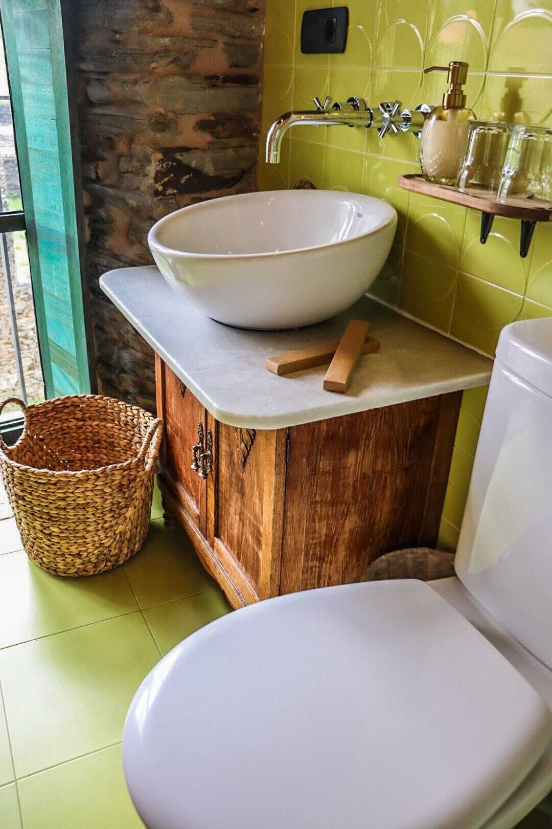 Un bagno con un ampio lavabo bianco a incasso, mobiletto in legno e water bianco.