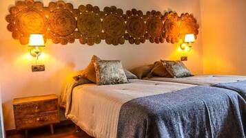 Un dormitorio con cama, almohadas, una mesita de noche y detalles decorativos en la pared.
