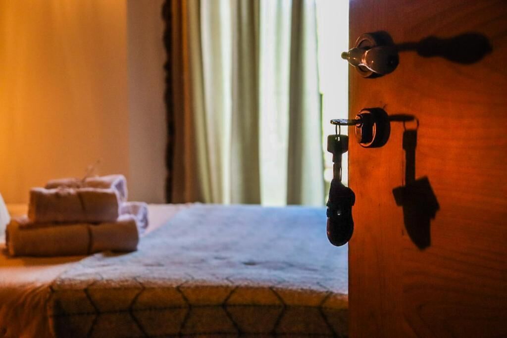 A hotel room with a bed, a set of towels, and a door with a lock and handle.
