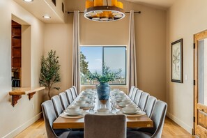 A dining room with a long table set for a meal, a large window with a view, and a hanging light fixture. - Villa Encanto- HEATED Pool & Spa, VIEWS, Outdoor Oasis (Paso Robles)