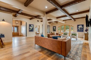 A spacious living room with a large sofa, wooden beams, and artwork on the walls. - Villa Encanto- HEATED Pool & Spa, VIEWS, Outdoor Oasis (Paso Robles)