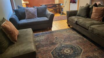 A living room with two sofas, a patterned rug, and a dining table.