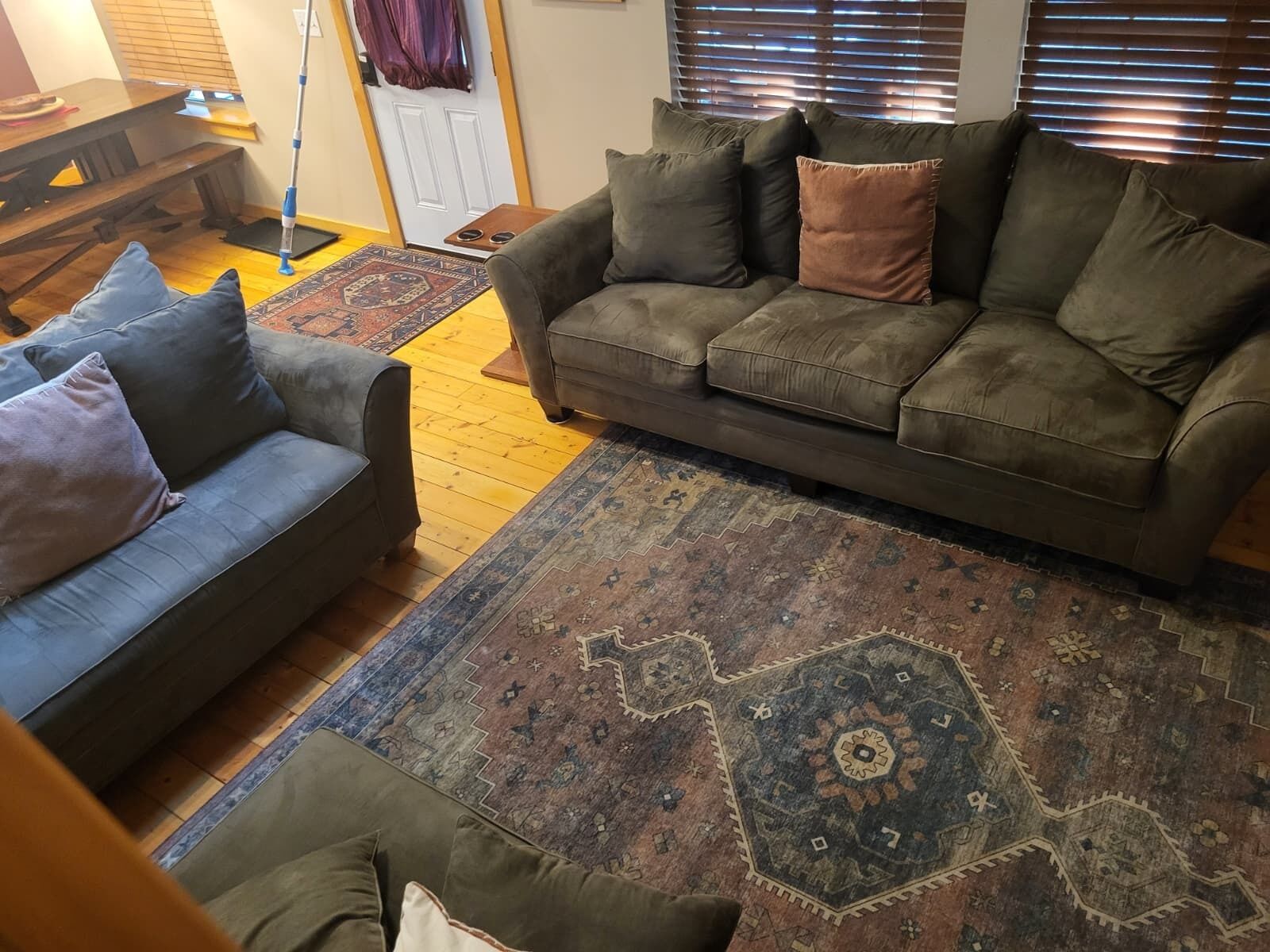 A living room with a sofa, a smaller couch, and a patterned rug.