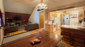 A modern kitchen with white appliances, a dining area with a wooden table, and a living room with a fireplace. - Mt. Baker Lodge  (Deming)