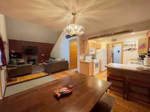 A modern kitchen with white appliances, a dining area with a wooden table, and a living room with a fireplace. - Mt. Baker Lodge  (Deming)