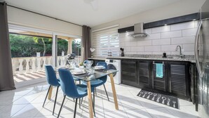A modern kitchen with a dining area, large windows, and a ceiling fan. - Aruba Oasis with pool, walking distance to the beach, hotels and restaurants (Palm Beach)