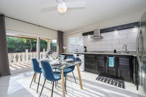 A modern kitchen with a dining area, large windows, and a ceiling fan. - Aruba Oasis with pool, walking distance to the beach, hotels and restaurants (Palm Beach)