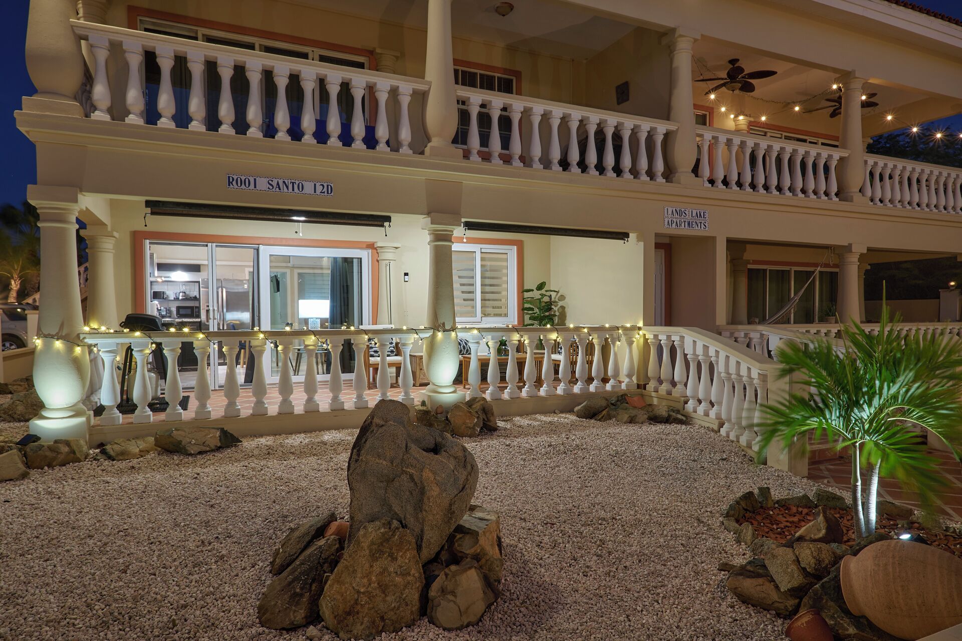 Un hotel con balcón, un letrero que dice "ROOTS SANTO 12D" y un anuncio para "LANDS LAKE APARTMENTS".