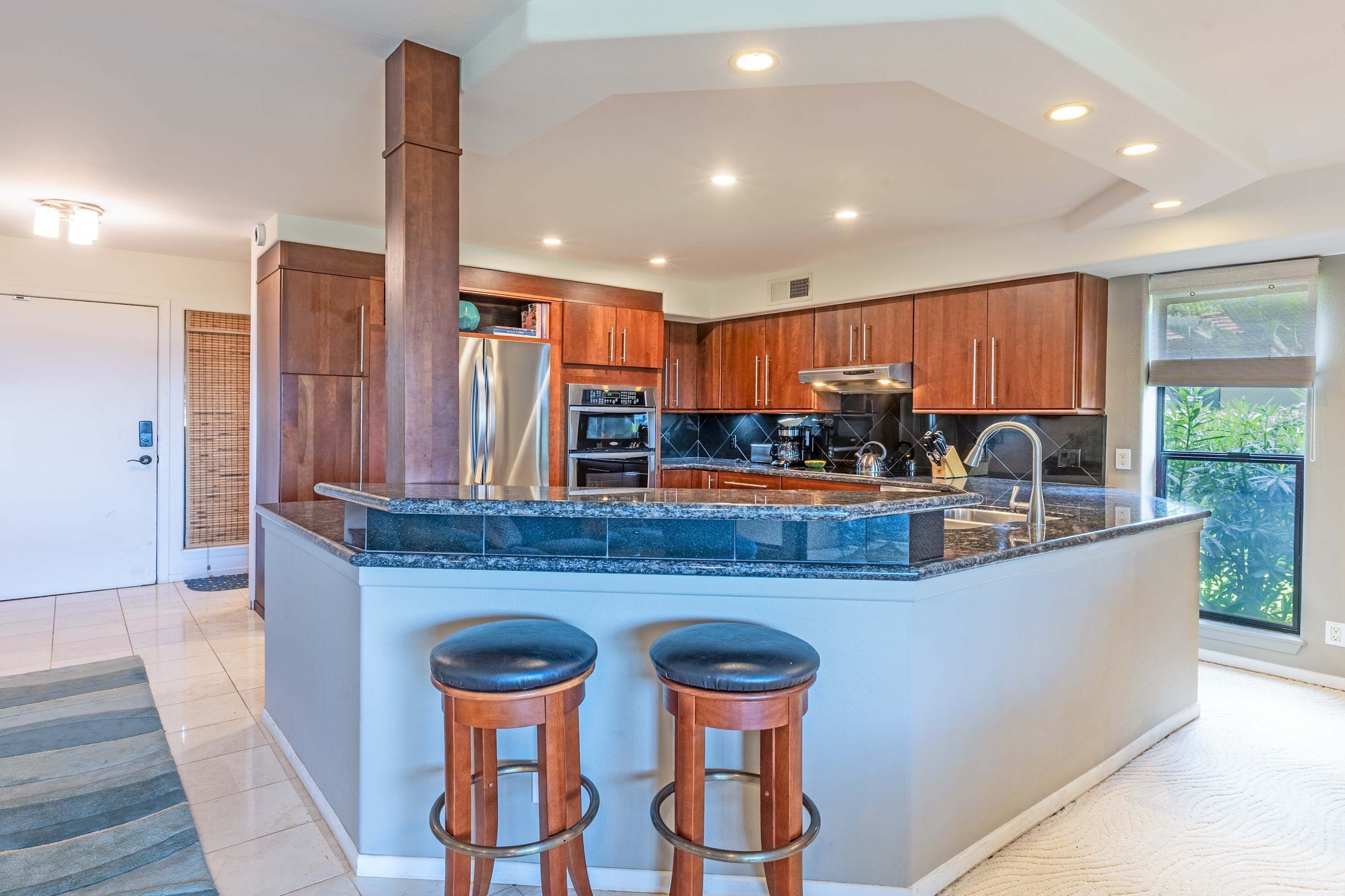 A modern kitchen with a large island, stainless steel appliances, and wooden cabinets.