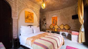 Een kamer met een bed, een klein tafeltje, een televisie aan de muur en een decoratieve boog.