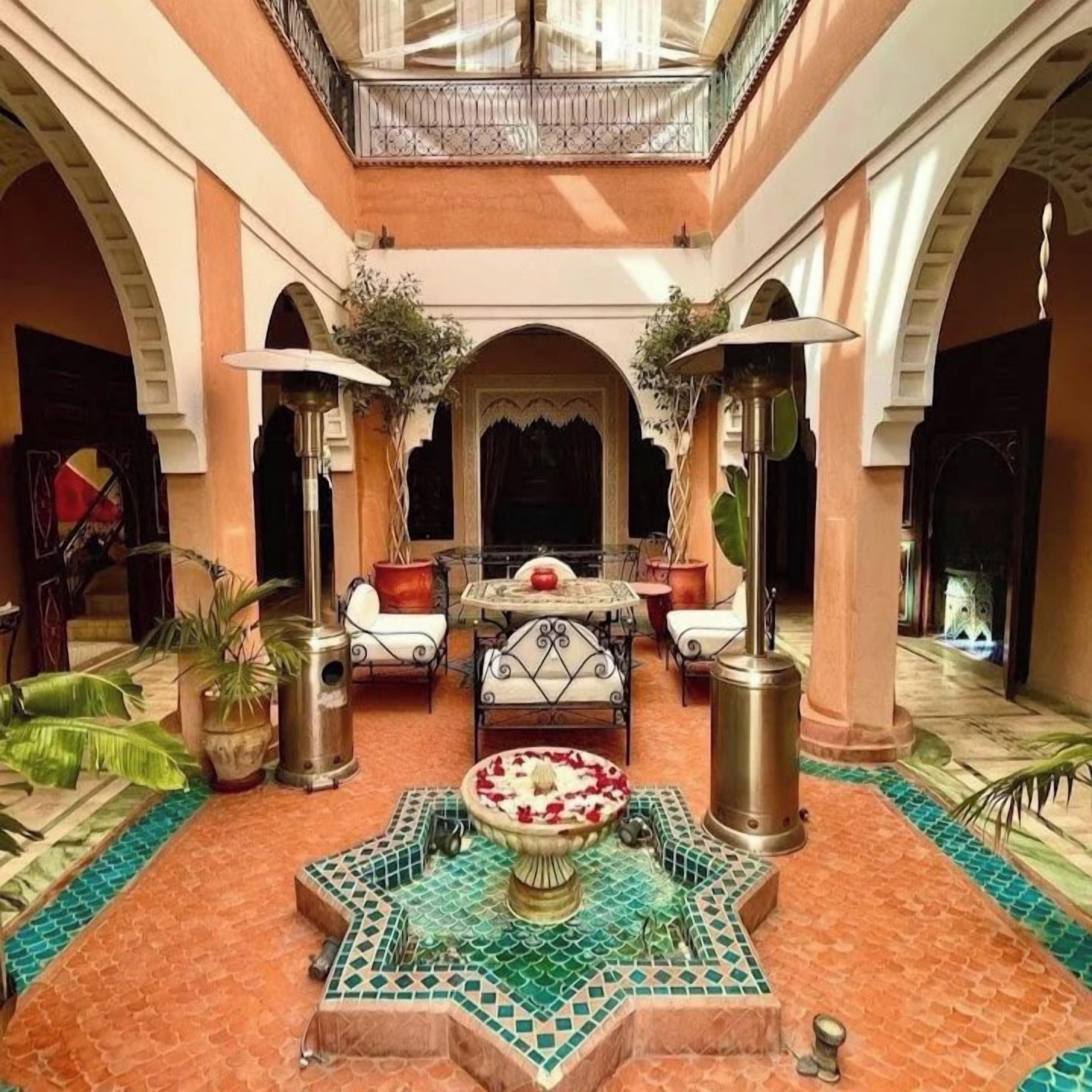 Un patio con una zona de estar central, una fuente y un balcón con vistas al espacio.