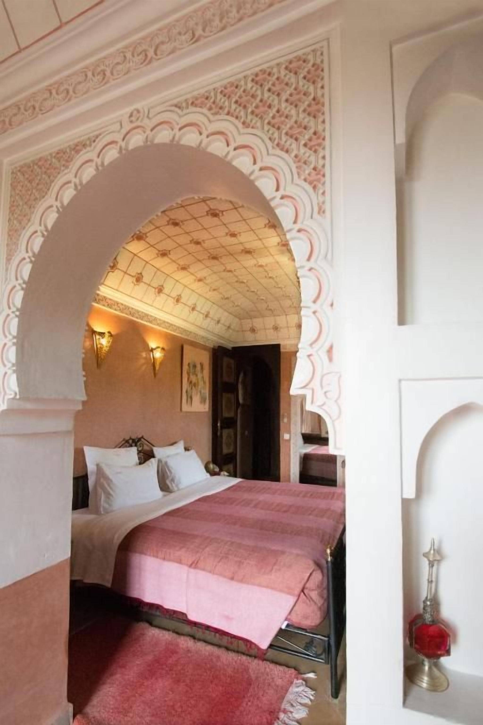 A room with two beds, a decorative archway, and a door with a keyhole.