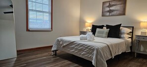 A neatly arranged bedroom with a bed, bedside lamps, and a window with blinds. - NEW! 2-bedroom townhome- 0.3 miles from I-81 (Glade Spring)
