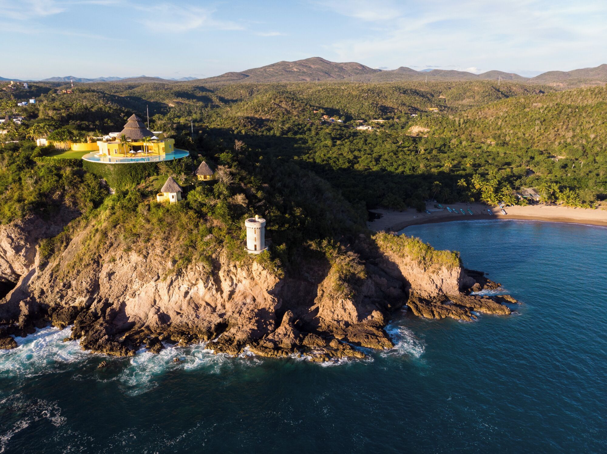 A coastal property with a cliffside, a swimming pool, and a beach.