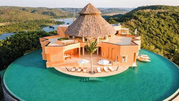 A resort with a thatched-roof structure, a pool, and a view of the surrounding landscape. - Careyes (Costa Careyes)