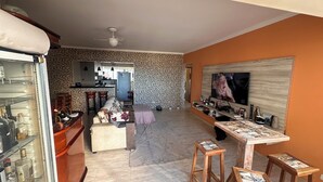 A living room with a sofa, a coffee table, and a TV. There is a kitchen in the background. - Vacation/Carnival - SEA VIEW 3 Bedrooms - Sleeps 10! (Praia Grande)