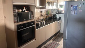 A kitchen with a microwave, oven, and refrigerator. There are cabinets, a sink, and various kitchen utensils. - Vacation/Carnival - SEA VIEW 3 Bedrooms - Sleeps 10! (Praia Grande)