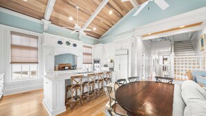 A spacious kitchen with white cabinetry, a wooden dining table, and a ceiling fan. - Blue Palmetto: Grayton Beach Retreat With Pool, Elevator, and 6-Passenger Electric Cart (Santa Rosa Beach)