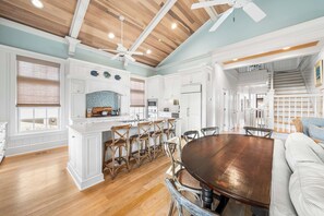 A spacious kitchen with white cabinetry, a wooden dining table, and a ceiling fan. - Blue Palmetto: Grayton Beach Retreat With Pool, Elevator, and 6-Passenger Electric Cart (Santa Rosa Beach)