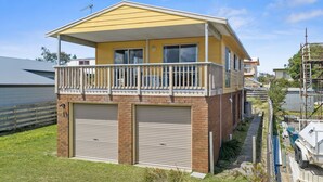 A two-story residential building with a balcony, two garage doors, and a visible satellite dish. - Neptune's Nook - Cape Paterson (Cape Paterson)