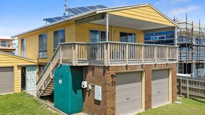 A two-story residential building with a balcony, solar panels, and a brick foundation. - Neptune's Nook - Cape Paterson (Cape Paterson)