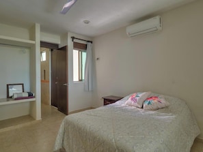 A bedroom with a bed, a wardrobe, a nightstand, and an air conditioning unit. - Casa de Mormor  - Yucatan Home Rentals (Chicxulub Puerto)