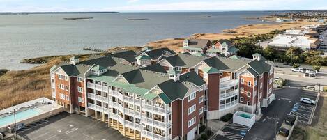 A multi-story hotel with a pool, parking, and views of the water.