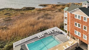 Ein Pool auf dem Dach mit Liegestühlen, Blick auf das Meer und ein Gebäude mit Ziegelverkleidung.
