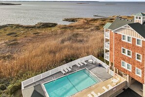 Ein Pool auf dem Dach mit Liegestühlen, Blick auf das Meer und ein Gebäude mit Ziegelverkleidung.