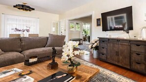 A living room with a sofa, coffee table, TV, and a cabinet. - Upscale San Diego Home with Secret Room & Private Yard! (San Diego)