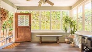 A sunroom with a wooden door, large windows, a ceiling fan, and a bench. - Upscale San Diego Home with Secret Room & Private Yard! (San Diego)