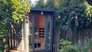 A small wooden structure with glass doors, a wooden deck, and a potted plant in a garden setting. - Upscale San Diego Home with Secret Room & Private Yard! (San Diego)