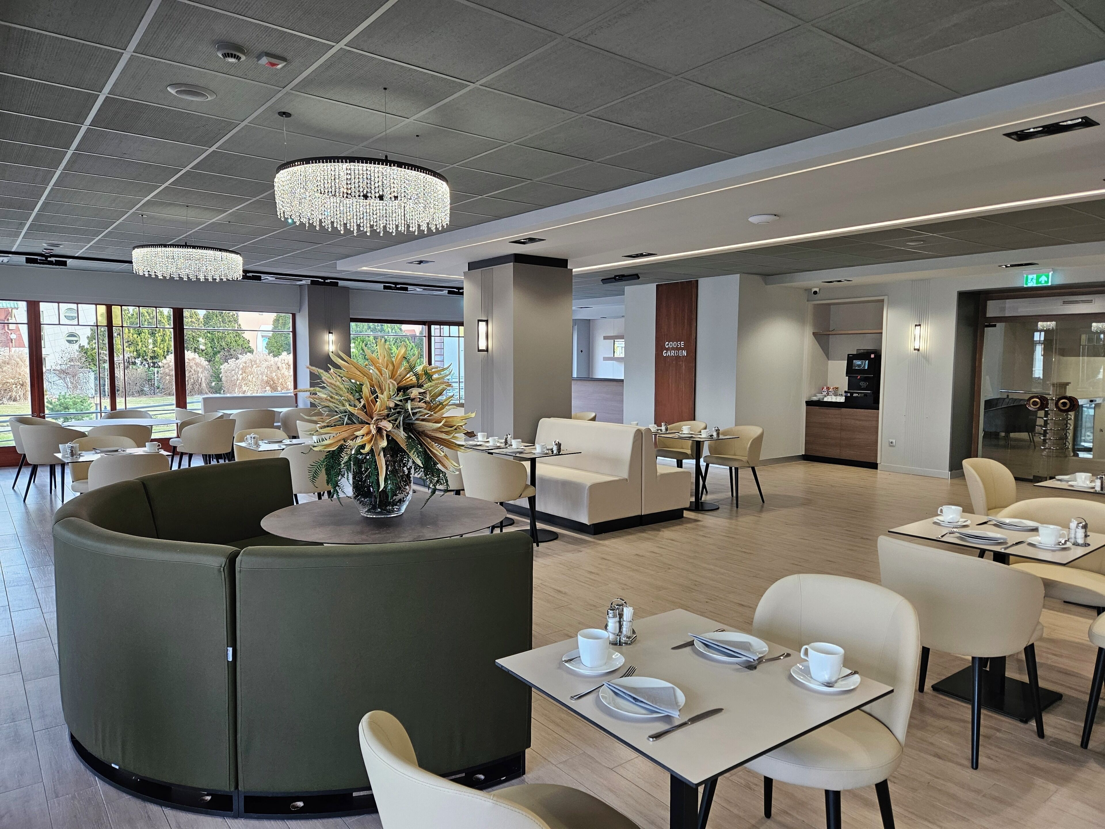 A modern dining area with round tables, cushioned seating, and a central decorative plant.