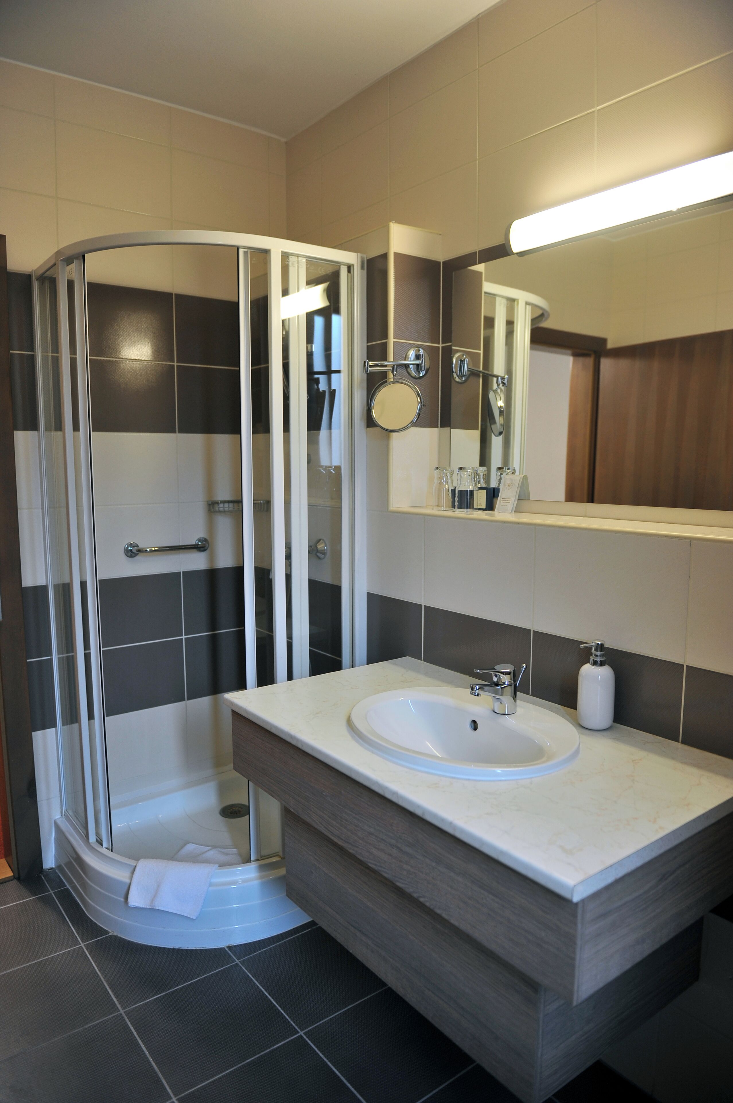 Une salle de bain moderne avec une douche à parois de verre, un lavabo avec un miroir et un porte-serviettes.
