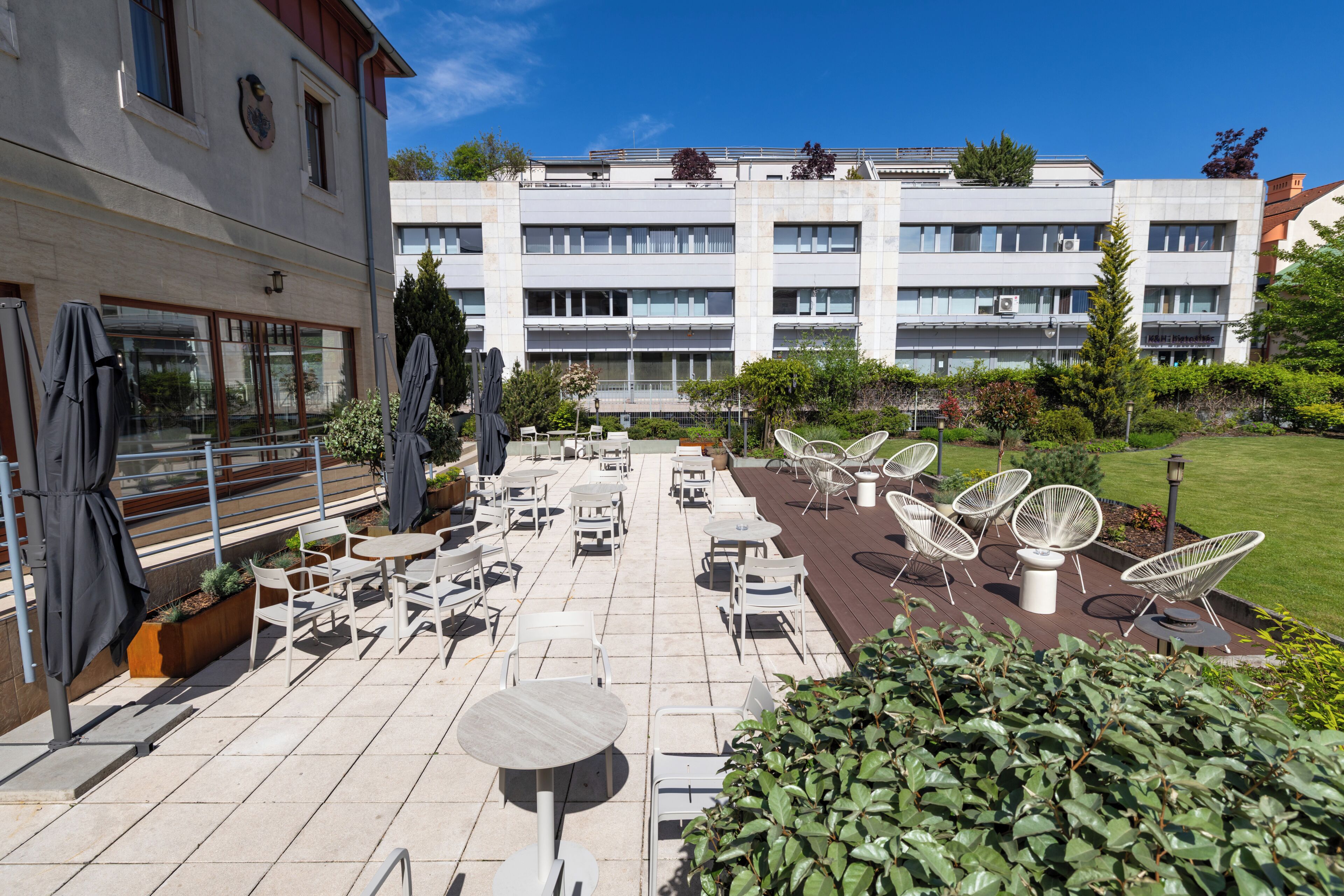 A courtyard with outdoor seating, a building with multiple windows, and a well-maintained lawn.
