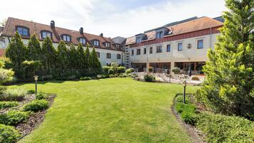 A courtyard with a lawn, surrounded by buildings with red-tiled roofs and multiple windows.
