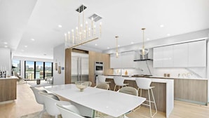A modern kitchen with a central island, white cabinetry, and contemporary lighting fixtures. - Hudson Views (North Bergen)