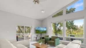 A spacious living room with a large sectional sofa, a wooden coffee table, and a TV mounted on the wall. - Sleeps 24 | Hot Tub | Firepit | 17 beds | 2 Houses (Oakhurst)