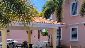 A swimming pool with a tiled deck, a covered seating area with tables and chairs, and palm trees. - Modern Townhouse Near Beaches & BQN Airport with Pool (Aguadilla)