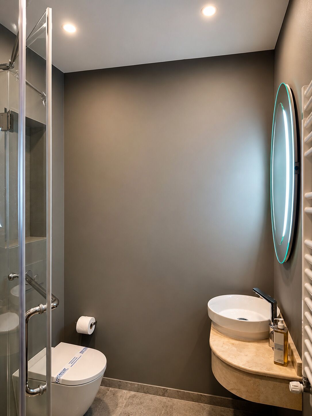 Un baño con cabina de ducha de vidrio, inodoro, lavabo con espejo y toallero.