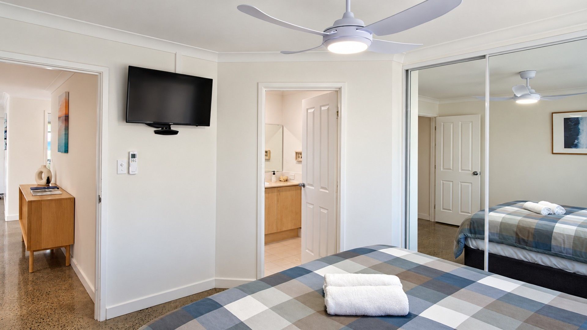 A hotel room with a bed, a television, a ceiling fan, and a bathroom visible through an open door.