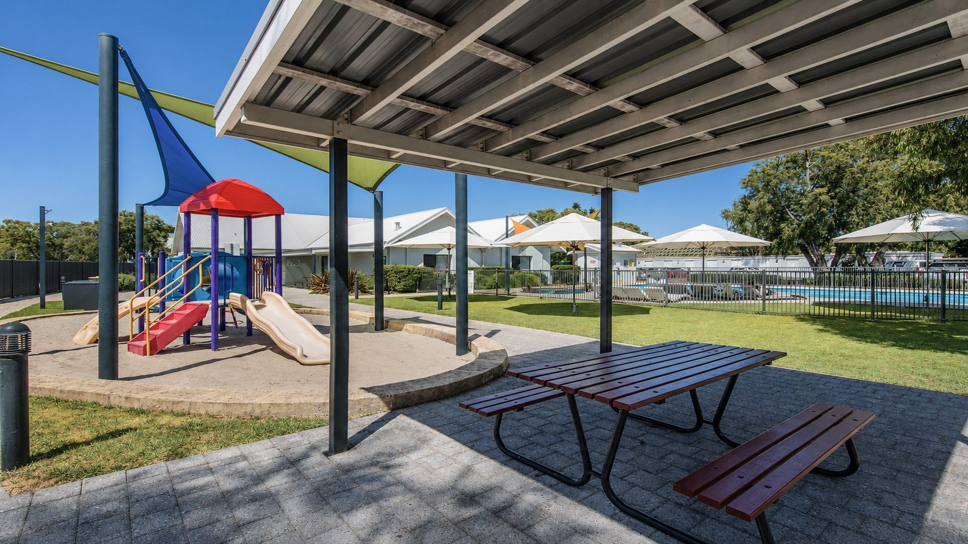 A playground with slides and a covered picnic area with benches.