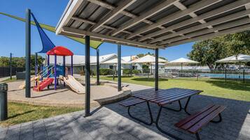 A playground with slides and a covered picnic area with benches.
