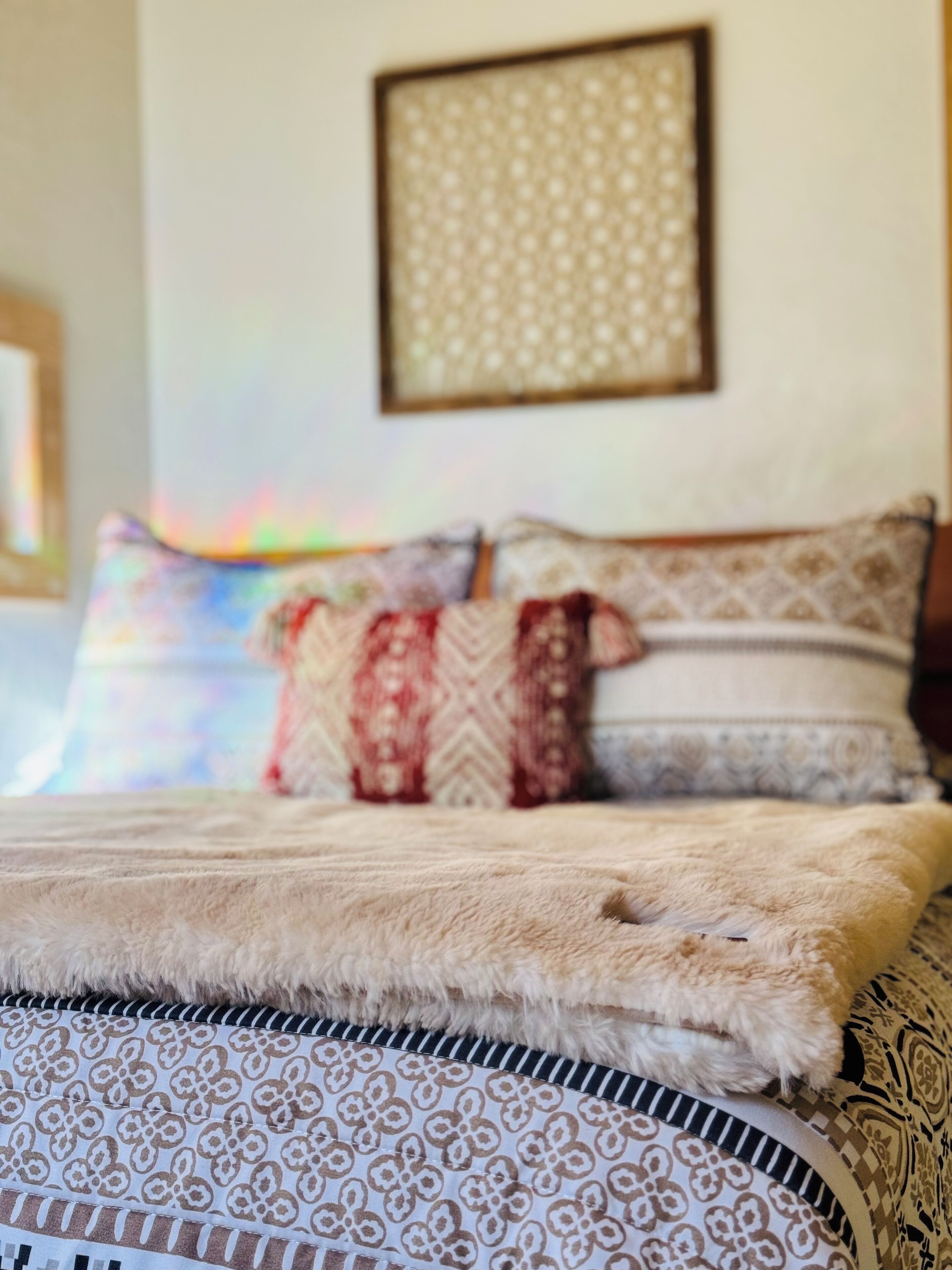 A bed with patterned bedding and a framed artwork on the wall.