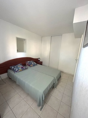 A bedroom with a bed, a nightstand, a mirror, and a wardrobe. - Very nice 3-room apartment with indoor pool and golf course view in Cap d'Agde (LE CAP D AGDE)