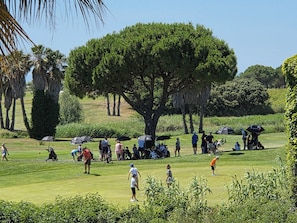 A golf course with people playing, trees, and umbrellas. - Very nice 3-room apartment with indoor pool and golf course view in Cap d'Agde (LE CAP D AGDE)