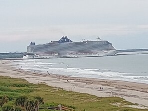 A large cruise ship docked at a port with a beach in the foreground.
