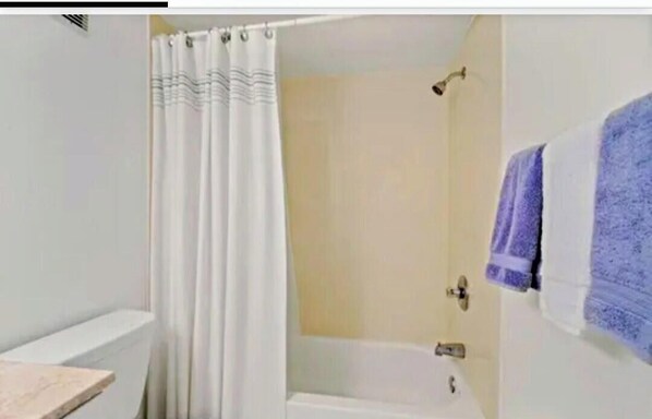 A bathroom with a shower curtain, a bathtub, and a towel hanging on the wall.