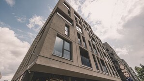 A modern building with multiple floors, large windows, and a clear sky with clouds. - Camelia Apartament Balkon Gara (Bydgoszcz)