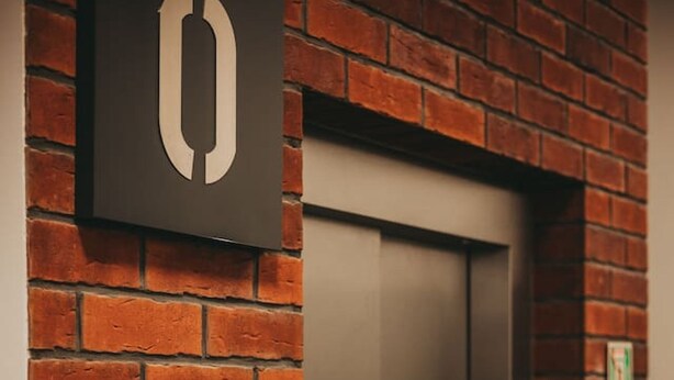 A brick wall with a door and an elevator. - Camelia Apartament Balkon Gara (Bydgoszcz)